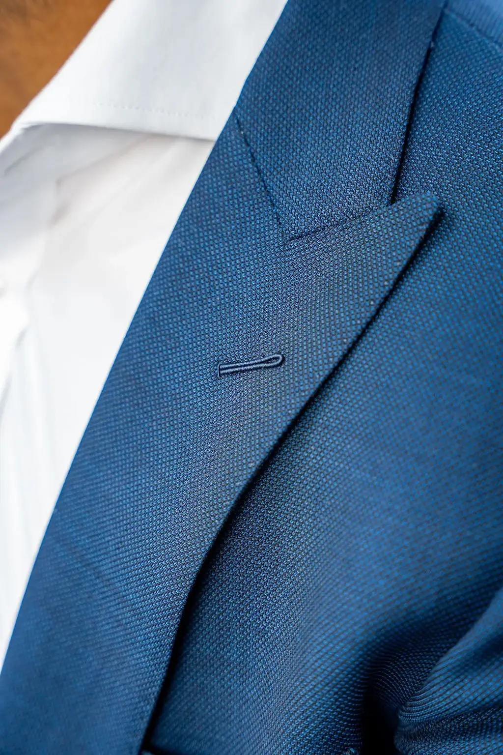 A tailor's hands meticulously stitching a lapel